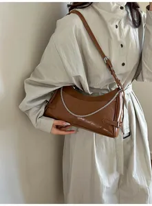 Détail du sac sous le bras en cuir marron vintage avec chaîne argentée et bandoulière réglable