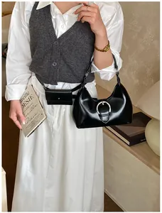 Détail du sac à main noir avec boucle fer à cheval argentée et mini pochette assortie