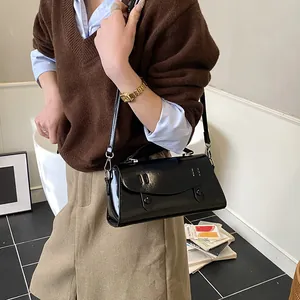 Classic black leather satchel bag with wave detail, worn by a model in casual attire