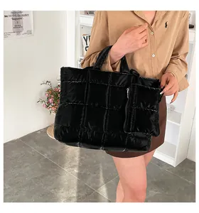 Détail d'un sac cabas noir matelassé avec une mini pochette assortie porté par un mannequin