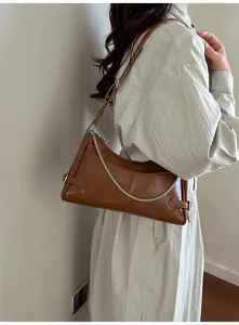 Détail du sac sous l'aisselle en cuir caramel avec chaîne argentée et boucle latérale
