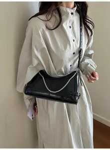 Détail du sac sous l'aisselle en cuir ciré noir avec chaînes argentées et boucle réglable