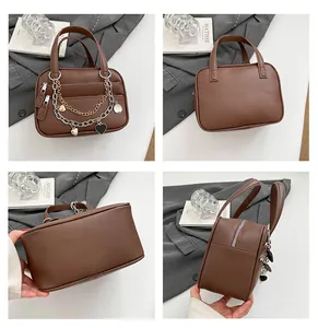 Detail view of a brown lychee pattern leather handbag with metallic heart chain charms