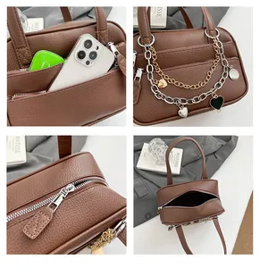 Detail of brown litchi leather handbag with dual metal chains and heart pendant