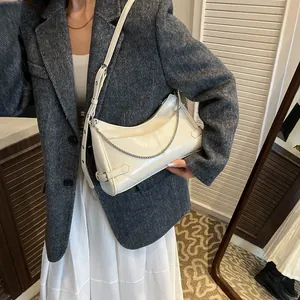 Sac hobo blanc cassé en cuir avec chaîne argentée porté par un mannequin élégant