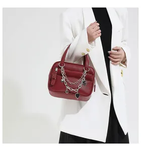 Detail of red lychee pattern leather handbag with gold and silver chain heart charms