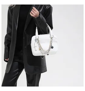 White pebbled leather handbag with layered gold and silver chains and heart pendant