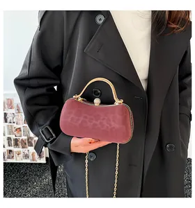 Detail of burgundy leopard print handbag with gold circular handle and diamond clasp