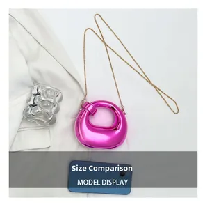 Size comparison of a mini rose pink crescent bag with gold chain and a smartphone