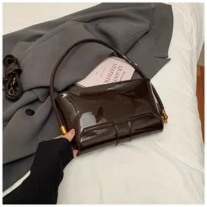 Vue détaillée du sac à bandoulière en cuir verni marron foncé avec finition brillante et boucles