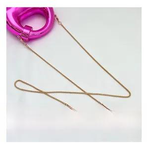 Detail of rose pink metallic crescent bag showing fine gold chain and mirror texture