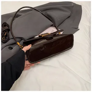 Vue détaillée du sac sous l'aisselle en cuir verni marron foncé et boucle dorée