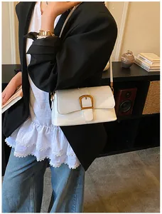 Gros plan d'un sac sous le bras en cuir verni blanc avec une grande boucle dorée sur un mannequin