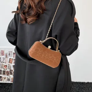 Brown suede evening crossbody bag with gold chain strap and pearl clasp on black coat