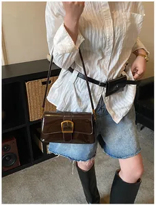 Détail du sac à bandoulière vintage en cuir verni avec grande boucle fer à cheval dorée brillante