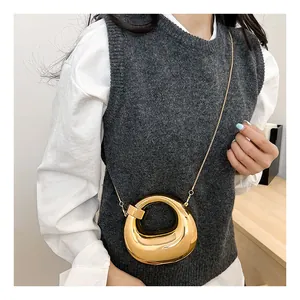 Close-up of golden crescent bag with mirror finish and delicate metal chain strap