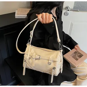 Detailed close-up of cream patent leather motorcycle style shoulder bag with silver hardware