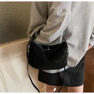 Detail of black suede shoulder bag with silver twist lock and minimalist design