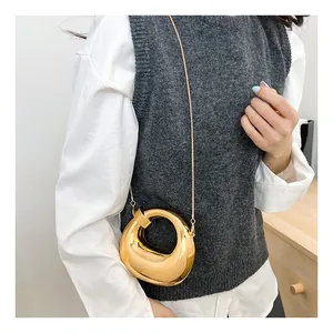 Golden crescent handbag with metallic mirror finish and chain strap shown on a model