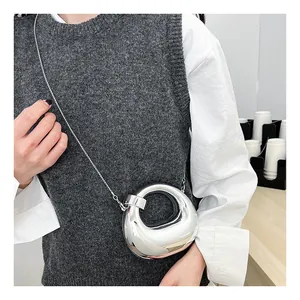 Model wearing a mini silver mirror crossbody bag with unique irregular ring shape and chain