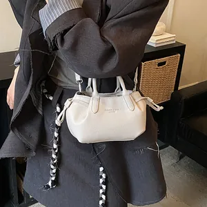 Minimalist beige lychee grain leather crossbody handbag shown in a lifestyle setting