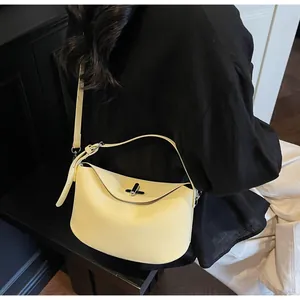 Detail of light yellow matte shoulder bag with silver metallic twist lock and slim strap
