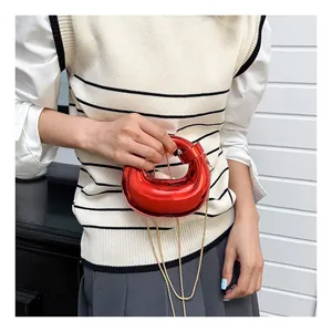 Close-up of metallic red crescent bag with glossy finish and delicate gold chain strap