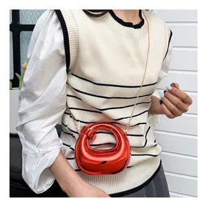 Red crescent mini crossbody bag with mirror finish and gold chain strap on model