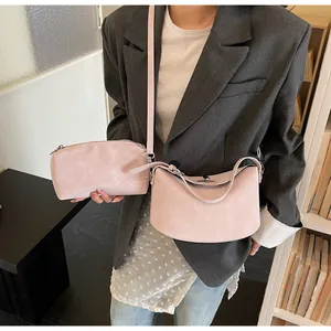 Detail of light pink crossbody and clutch set with matte texture on a grey blazer