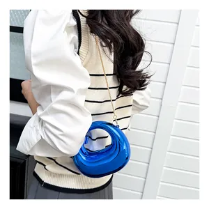 Detail of blue crescent mini bag with glossy mirror finish and gold chain strap