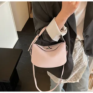 Detail of light pink leather crescent bag with metal clasp and adjustable strap
