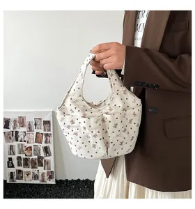 Dettaglio della borsa in velluto a coste bianco crema con fiocchi e tasche laterali