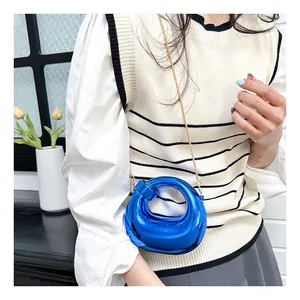 Blue crescent ring bag with mirror finish and gold chain worn by a model