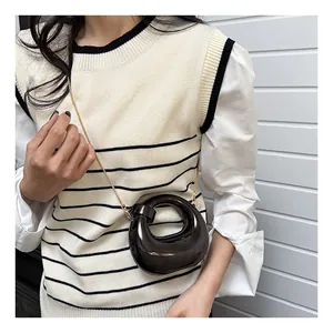 Detail of a black avant-garde mini crossbody bag with a hollow ring design and gold chain