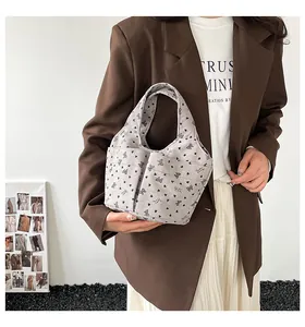 Borsa tote in velluto a coste grigio chiaro con motivi a cuore su una modella