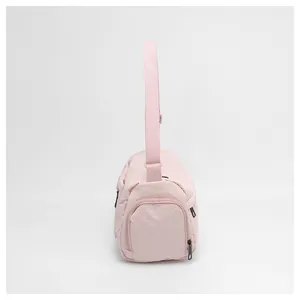 Détail du sac bandoulière en nylon rose montrant la poche latérale et la sangle large