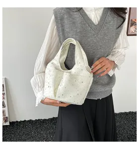 Dettaglio della borsa a secchiello in tela bianca con stampe di stelle e tasche