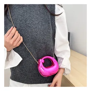 Detail of pink mirror metallic crescent bag with elegant gold chain shoulder strap