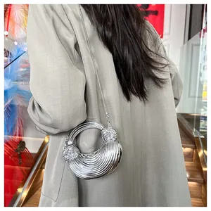 Détail du sac croissant argenté avec texture sculpturale et bandoulière en chaîne