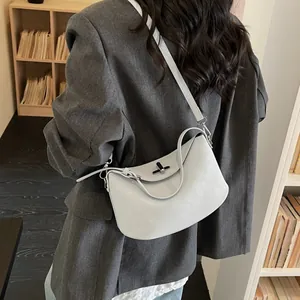 Minimalist light blue-grey leather handbag with adjustable strap shown on a model