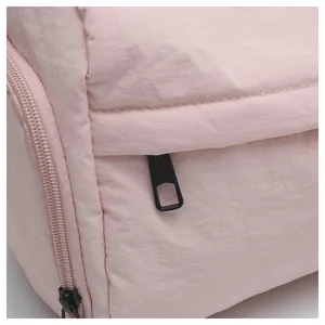Détail d'un sac en nylon rose montrant le zip et la texture des coutures