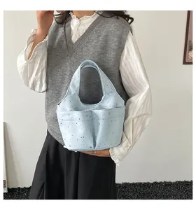 Dettaglio della borsa in tela azzurra con stelle argentate e doppie tasche frontali