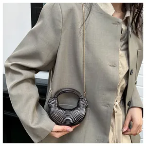 Détail du sac croissant gris montrant la texture ondulée et la bandoulière dorée