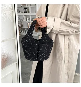 Dettaglio della borsa tote in tela nera con stampe di fiocchi bianchi e tasca esterna