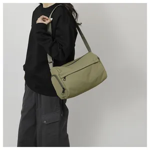 Sac de sport en nylon vert armée avec poches zippées porté par un mannequin en bandoulière