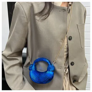 Gros plan sur le sac croissant bleu métallisé montrant la texture et la chaîne dorée