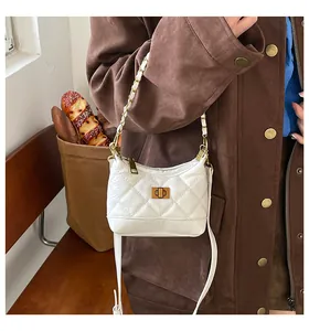 Détail du sac matelassé crème avec fermoir doré tournant et bandoulière chaîne en cuir