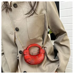 Détail du sac croissant rouge avec texture plissée et bandoulière chaîne dorée