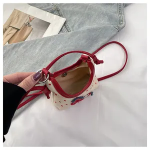 Detalle del mini bolso de lona con lunares rojos y cierre magnético de dinosaurio animado