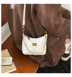 Détail d'un sac bandoulière blanc matelassé avec chaîne dorée sur un mannequin en manteau
